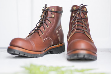 ฺBrown leather shoes with vintage camera on a wooden floor.Brown vintage leather boots aligned selective focus.Men leather shoes 