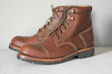ฺBrown leather shoes with vintage camera on a wooden floor.Brown vintage leather boots aligned selective focus.Men leather shoes 