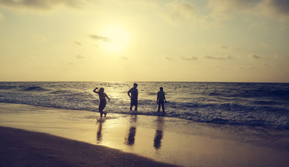 Fototapeta na wymiar Father with two kids enjoying summer vacation on the beach