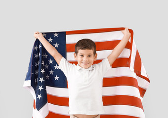 Little boy with USA flag on light background. Memorial Day celebration