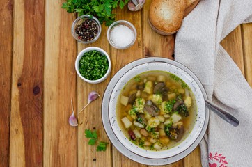 Soup with beans, mushrooms and dumplings in a bowl on a dark wooden background with herbs and garlic. Vegan (lean) dish. Rustic style.