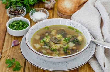 Soup with beans, mushrooms and dumplings in a bowl on a dark wooden background with herbs and garlic. Vegan (lean) dish. Rustic style.