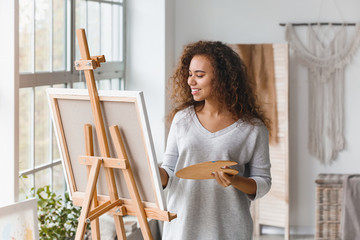 Beautiful female African-American artist painting in studio