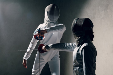 Fencer woman with fencing sword. Fencers duel concept.