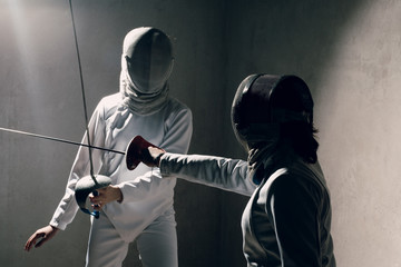 Fencer woman with fencing sword. Fencers duel concept.