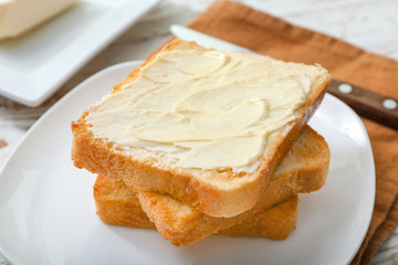 Tasty toasted bread with butter on plate, closeup