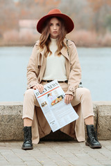 Portrait of stylish young woman with newspaper outdoors