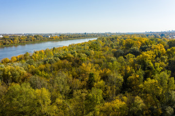 Flight of a drone over the Vistula River in a suburb of Warsaw, Poland. Aerial view of a beautiful autumn landscape with forest and river at sunset.