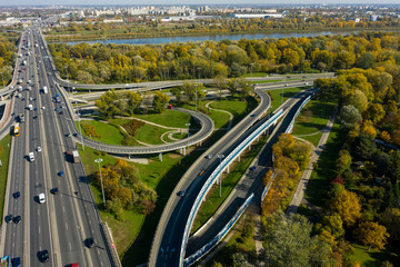 Fototapeta premium Aerial shot of big freeway intersection in Warsaw, traffic going fast through many road flyovers. Aerial view of a motorway with several traffic intersections in Warsaw, 