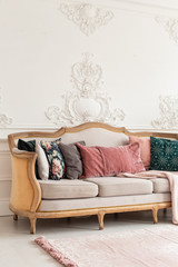 Sofa with lots of pillows stands in white appartment room
