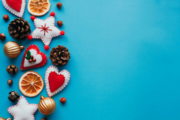 Copyspace flat lay of Soft felt toys like stars, hearts and pine cones on the blue background. New year backgrounds concept. Festive christmas flatlays of decorations concept.