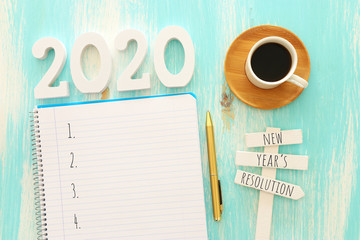 Naklejka premium Business concept of top view 2020 goals list with notebook, cup of coffee over blue wooden desk
