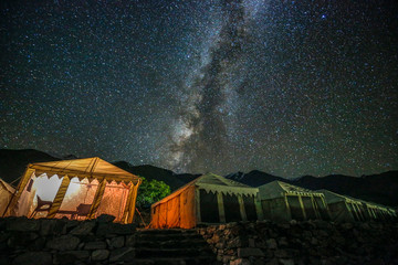 Milkyway galaxy  shining above illuminated tents near pangong lake, ladakh