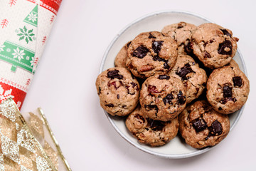 Christmas cherry, pecans and chocolate oatmeal cookies and gift wrap on white background. Holydays tasty gift. Selective focus