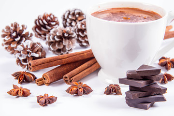 Cup of hot chocolate with cinnamon, anise stars, pieces of dark chocolate and some cones	