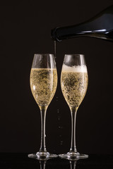 Two glasses with white wine and champagne next to the bottle on a colored background