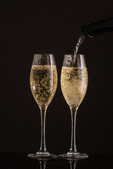 pour champagne in two glasses on a white or black background