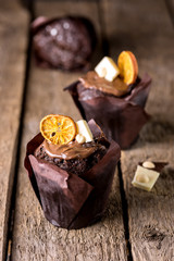 Three Tasty Homemade Chocolate Muffins in Paper Decorated with White Chocolate and Dried Citrus Vertical Wooden Background Holiday Christmas Dessert