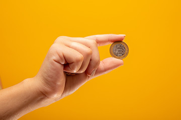 Hand holding one Real coin of Brazil on yellow background. Finance concept. - obrazy, fototapety, plakaty
