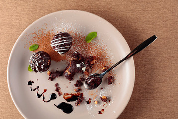Chocolate balls with mint on a beige plate.