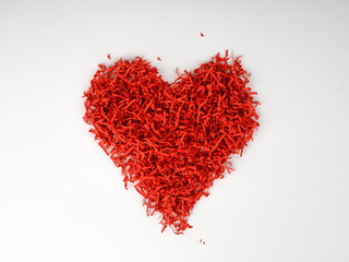 Fototapeta na wymiar Red shredded paper in shape of heart on blue background. Heart made of shredded paper. Recycling concept. decaying heart