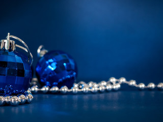 Blue Christmas ball with silver beads. Bokeh effect on dark background. Copyspace for your greeting or wishes, banner