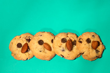 Picture of 4 cookies stack On a turquoise blue background The ingredients are grains without baking powder, contains almonds, pumpkin seeds, chocolate chips, raisins.