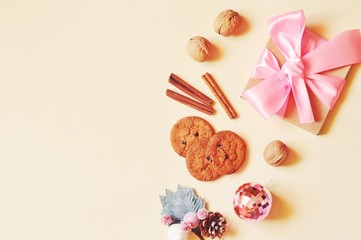 Wrapped gift box with pink bow ribbon, Cinnamon sticks and pink shiny ball. Flat lay Christmas and New Year present and sweets