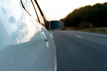 Beside of white car on the road with blurred nature forest.