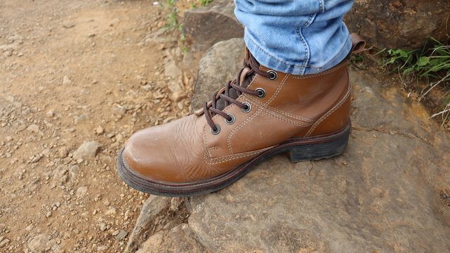 A pair of brown leather boots over a mountain rock. Trekking shoes are new men's fashion.