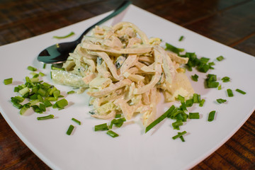 Squid salad on a large white plate on a wooden table