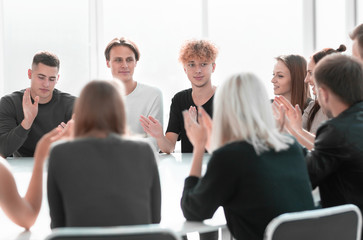 group of young people applauding sitting at a round table.