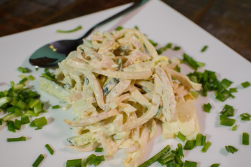 Squid salad on a large white plate on a wooden table