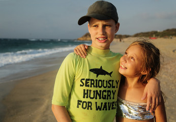Portrait of two happy kids on the beach. 11 years old austic brother with 8 years old sister