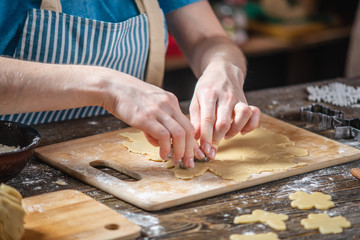 Woman rolls out the dough with a rolling pin and shapes gingerbread. Christmas mood for cooking delicious cookies.