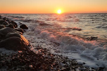 Obraz premium waves with surf foam at the shore line at sunset