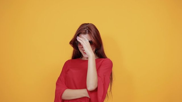 Delighted red lady is receiving compliments on her new looks as she winks by removing her glasses. She is smiling as she is relaxed and enjoying her moments.