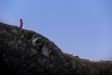 Woman looking at the horizon on top of cliff at blue hour