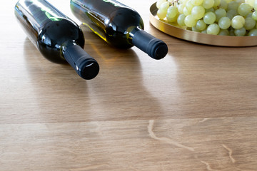 Obraz premium Bunch of grapes and a bottle of organic wine on a wooden table as a background. Front perspective view. Copy space in front of the picture.