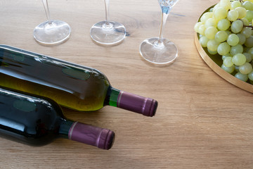 Obraz premium Bunch of grapes and a bottle and wine glasses wine on a wooden table as a background. Front perspective view. It’s party time.