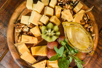 Cheese platter on a wooden plate on a large wooden table