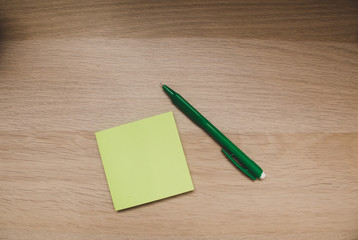 note and pen on wooden background