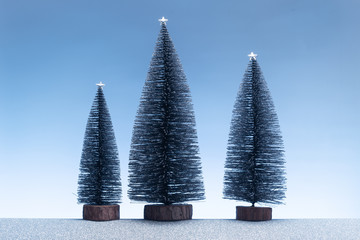Christmas background. Minimalist scene with miniature fir trees and sparkly silver ground and blue sky