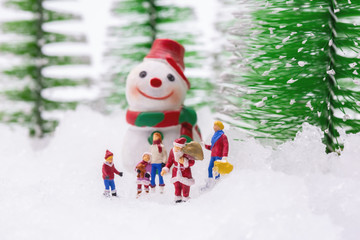 Happy snowman on snow with background of blurred Christmas pine. Miniature people in Christmas Theme.  