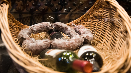 Still life products and alcohol. Good cured sausage and bottles of red wine are located in the basket.