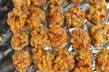 Top view, close up of rows of freshly prepared clams casino, sprinkled with paprika before baking on a sheet of tinfoil, covered baking sheet