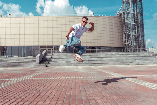 Young and active dancer dancing in jump, sport man, summer city, break-dancer pose, hip-hop movement, modern dance style, youth lifestyle. Street urban fitness motivation. Free space for copy text.