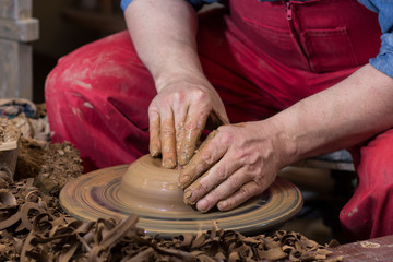 Professional male potter making ceramics on potters wheel in workshop, studio. Close up shot of...