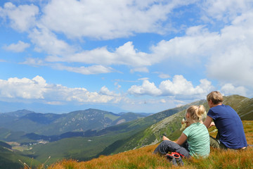 Mother and daughter sitting on the hill and watching mountain view