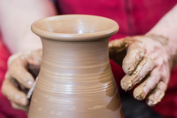 Professional male potter making ceramics on potters wheel in workshop, studio. Close up shot of potters hands. Handmade, art and handicraft concept